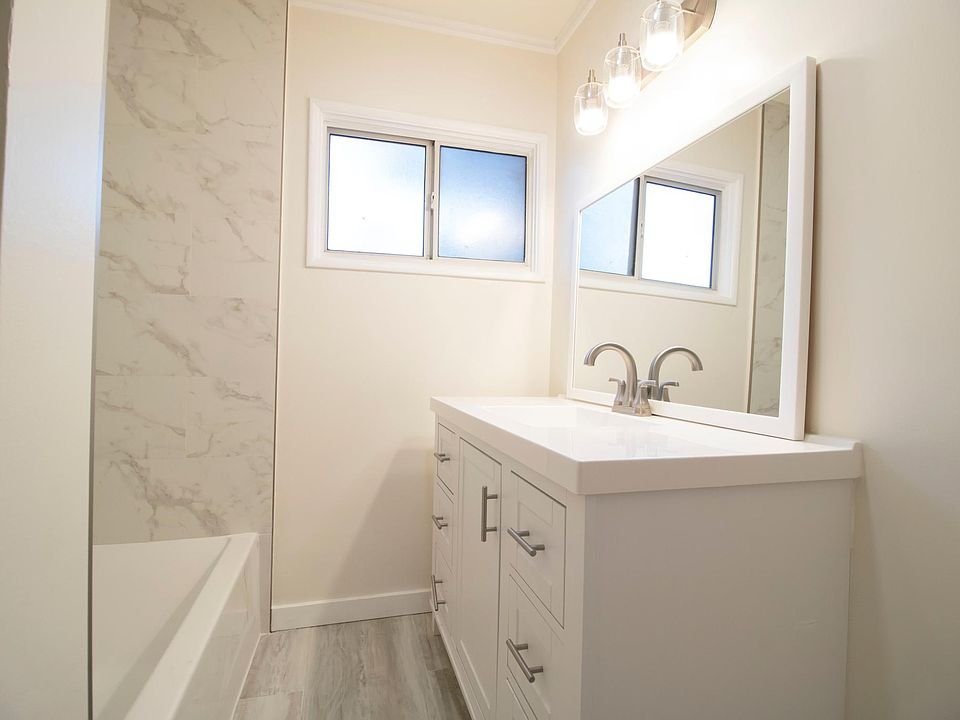 Bathroom in California with a white vanity, sleek faucet, and large mirror.
