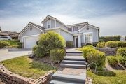 Two-story house with gray siding, white trim, and a gabled roof in California