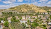 Aerial view of a neighborhood in California with houses, green trees and hills