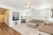 Living room with a beige sofa, white walls, a ceiling fan, built-in shelves with a TV in California.