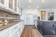 Kitchen in California with white cabinets, granite countertops, and wooden floor.