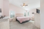 Bedroom in California with pastel pink walls features a large bed with a pink comforter