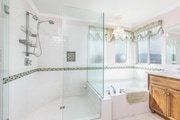 Bathroom with glass shower, beige tiles, and wooden vanity in California.