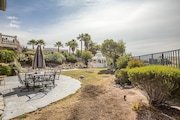 Backyard with patio set umbrella, green shrubbery, and distant palm trees in California.
