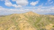 California aerial view of dry hills under blue sky with scattered clouds