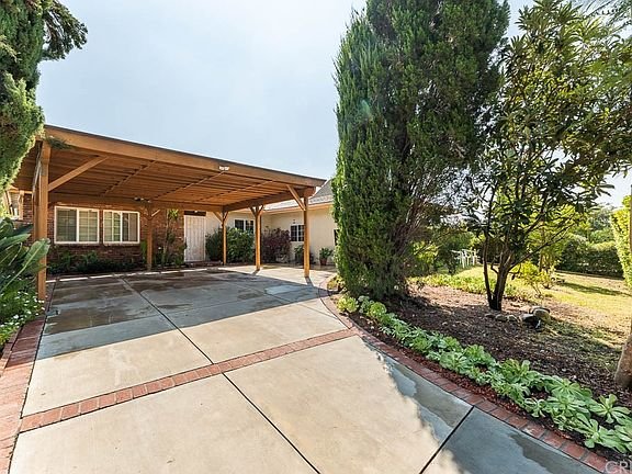 Driveway with wooden carport, trees and shrubs in California