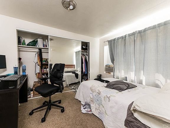 A bedroom in California with a computer desk, chair on the left and bed.