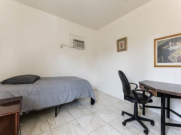 Bedroom in California with a single bed, gray bedding, and a wooden desk.