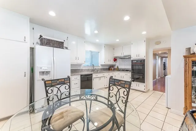 Kitchen with white cabinets, stainless steel appliances, and a glass dining table in California