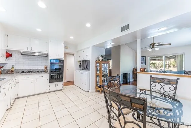 Kitchen in California with white cabinets, tiled floor, and a glass dining table