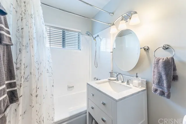 Bathroom in California with white cabinet, round mirror and a white vanity