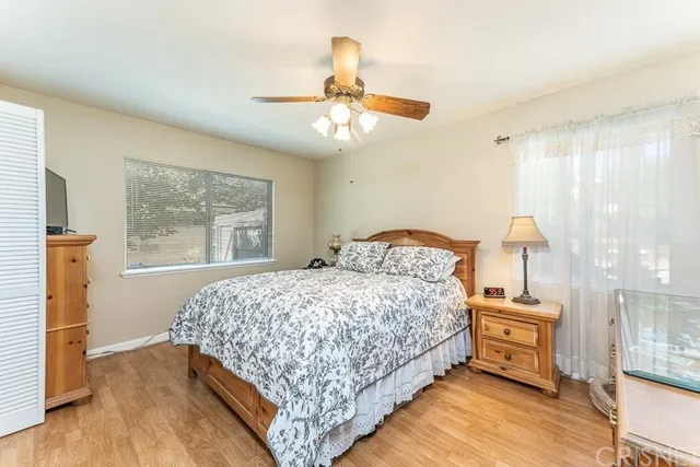 Bedroom in California with wooden furniture, ceiling fan and floral bedding
