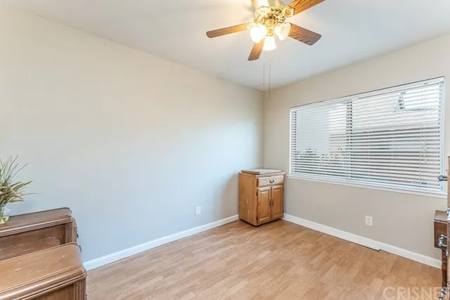 Room in California with light colored walls and wood flooring, ceiling fan and wooden cabinet