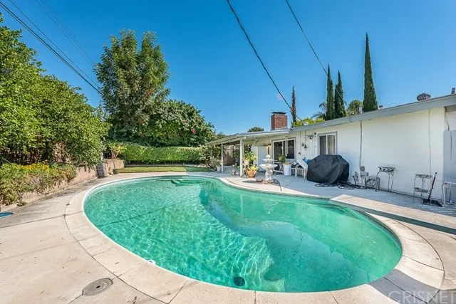 Backyard with round pool with bushes, and trees in California