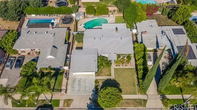 Aerial view of suburban homes in California with grey roofs, swimming pools and trees.