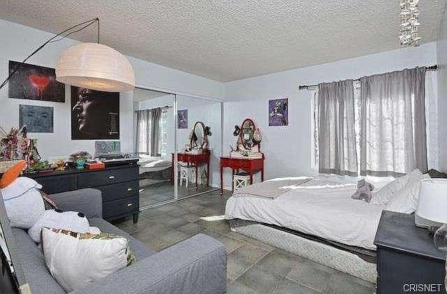 Bedroom with gray sofa, a bed and mirrored closet doors in California