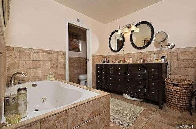 Bathroom in California with a tiled jacuzzi tub and vanity with round mirrors.